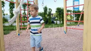 4k视频可爱的小男孩投掷和试图抓住大绳在操场上攀爬